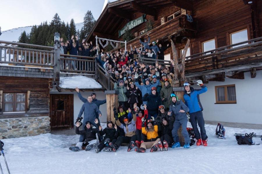 Große Gruppe auf der Treppe einer Almhütte im Schnee