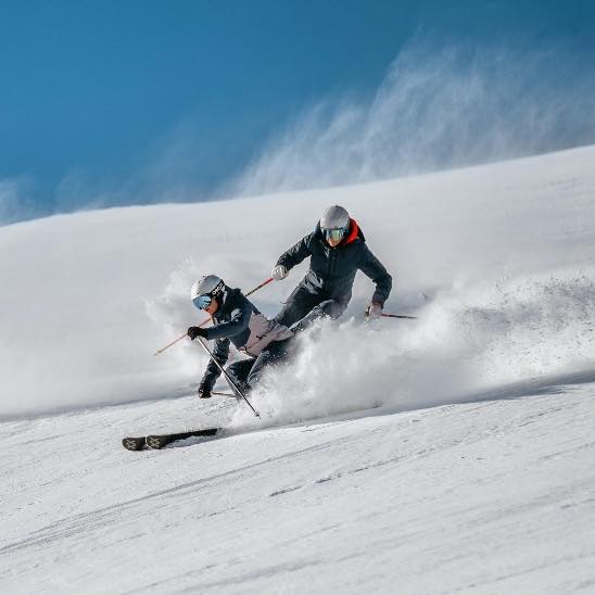 Zwei Skifahrer in einer Staubwolke im Tiefschnee