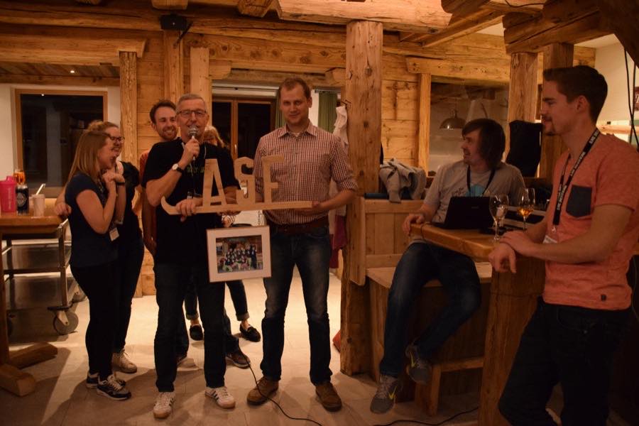 Mitglieder in einer Hütte, eine Person hält ein gerahmtes Bild